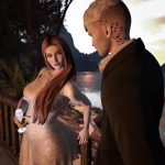 Woman in champagne dress leaning toward her suited partner with a lake view