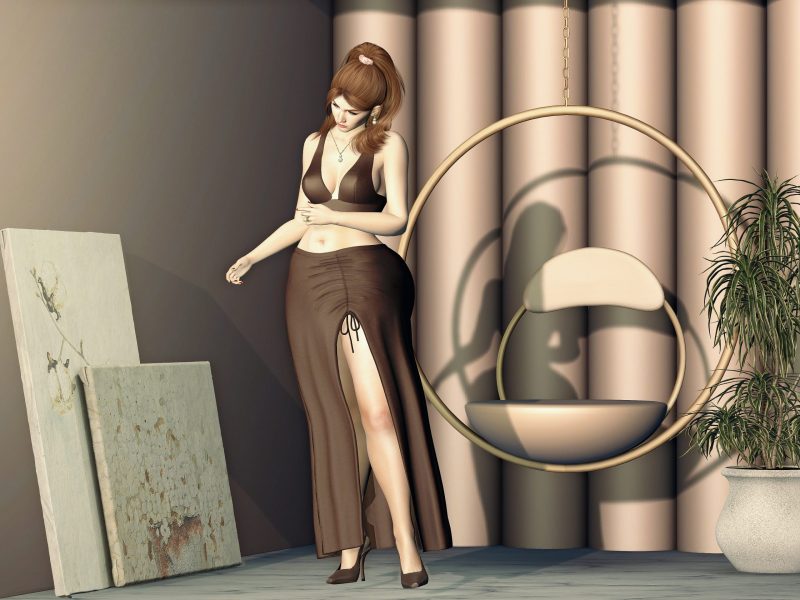 Second Life avatar wearing a brown crop top and slit skirt, standing gracefully near a hanging chair with head tilted down.