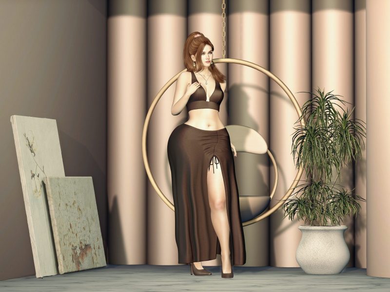 Virtual fashion look in Second Life showing an avatar in a brown crop top and slit skirt, standing gracefully with hand at necklace.