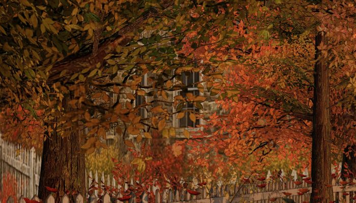 Autumn leaves framing the view of a stone cottage behind the fence