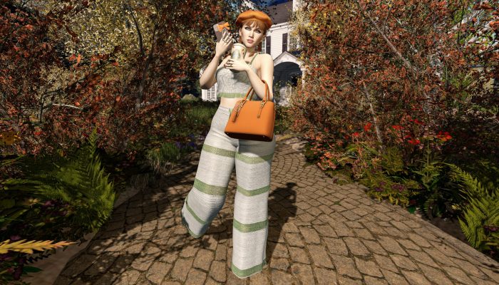 Model posing with pumpkin spice latte and orange handbag, autumn foliage all around.